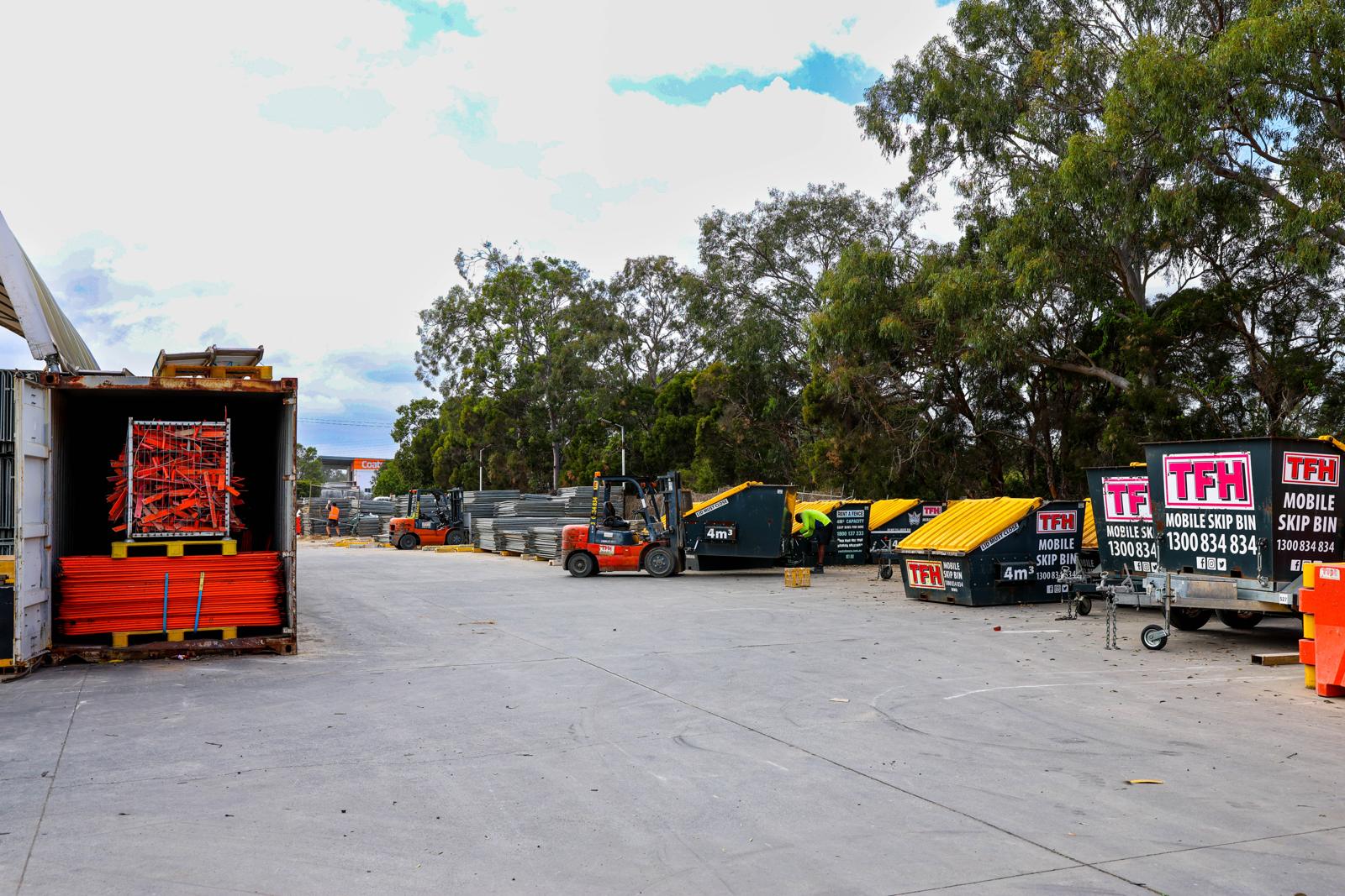The TFH Brisbane yard: fence panel stacks, crowd control barriers, forklifts and mobile skip bins